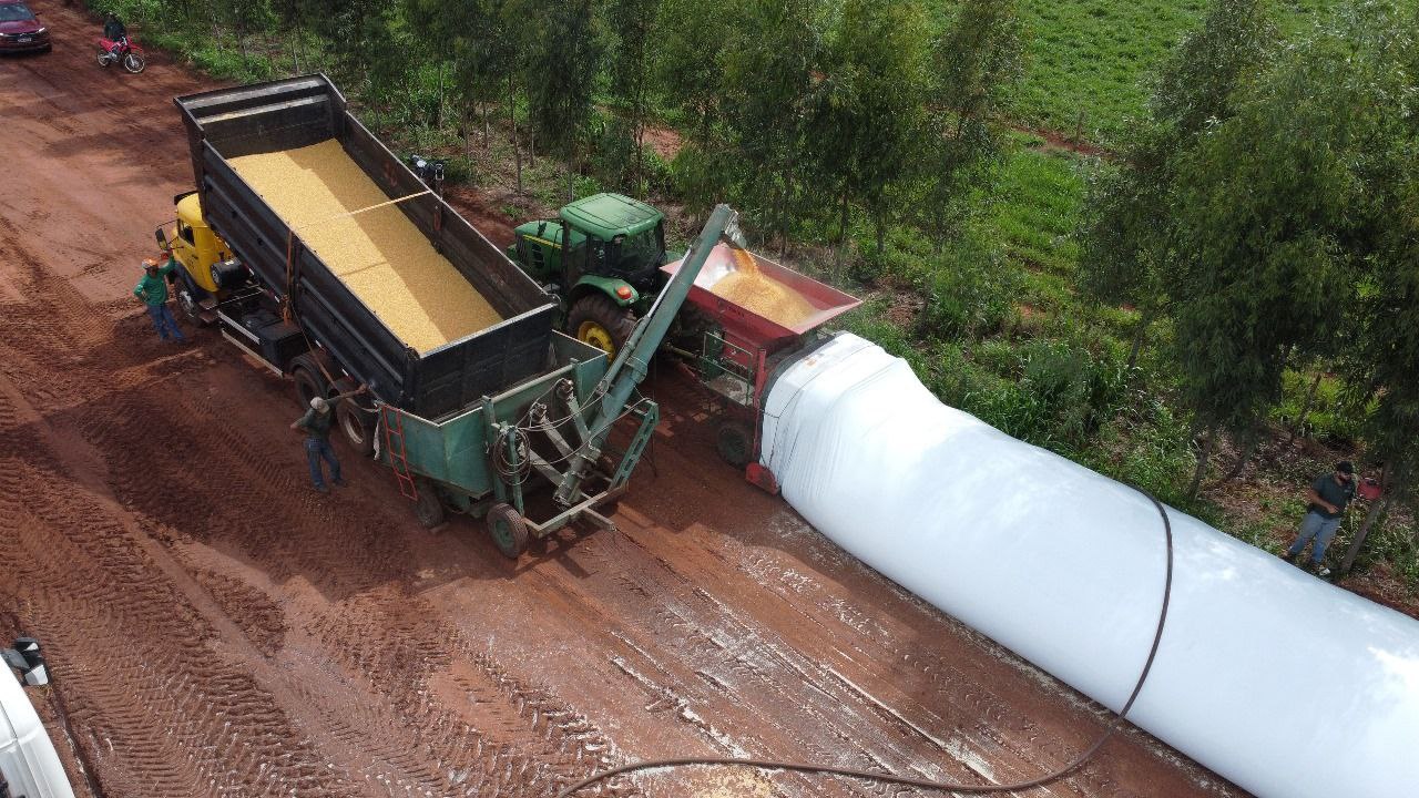 Embutidora transferindo milho de uma carreta basculante para o silo-bolsa